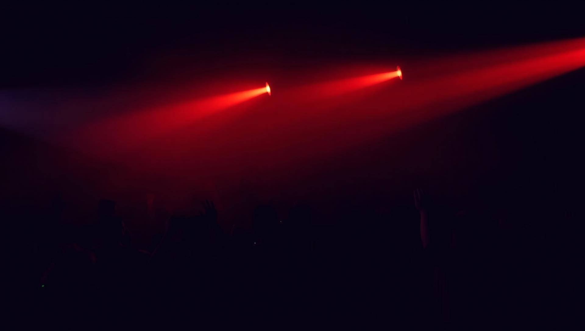 Club mit warmen roten Lichtstrahlen über tanzendem Publikum